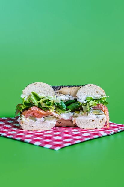 <p><b>El bagel</b> es un pan bastante denso cuya masa se suele personalizar con especias, semillas o cereales, algo que da mucho juego para elaborar todo tipo de bocadillos creativos. Una salsa con textura cremosa y algunos vegetales crudos –además de una proteína no demasiado pesada o, si es así, en poca cantidad– serán sus mejores acompañantes.</p> <p><em>Ingredientes: Un bagel al gusto (con sésamo, semillas de amapola, queso…), 80 gramos (unas 2 cucharadas) de queso de untar a temperatura ambiente, 80 gramos (dos o tres lonchas) de salmón ahumado, entre 2 y 4 pepinillos agridulces, una cucharadita de cebollino picado, una cucharadita de perejil picado, ¼ de cucharadita de ralladura de limón (solo la parte amarilla), ¼ de cucharadita de pimienta recién molida, ½ taza de mezcla de hojas verdes.</p></em> <p><em>Preparación:</em> Mezclar el queso con el cebollino, el perejil, la ralladura de limón y la pimienta. Abrir el bagel y untar con la crema de queso por los dos lados, poner una capa de pepinillos cortados en láminas, el salmón y las hojas verdes. Tapar con el otro medio bagel y servir.</p>
