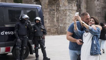 Una pareja se hace una fotografía ante una pareja de mossos. 