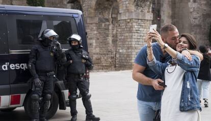 Una pareja se hace una fotografía ante una pareja de mossos.