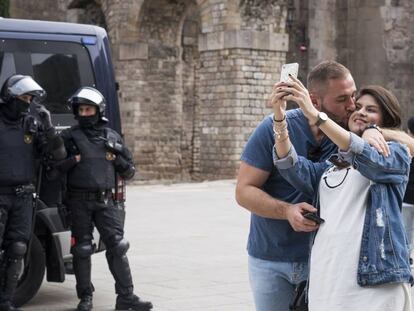 Una pareja se hace una fotografía ante una pareja de mossos. 