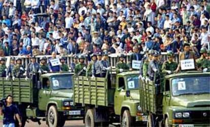 Miles de espectadores contemplan en un campo de ftbol cmo un grupo de condenados a muerte es conducido al patbulo en camiones.