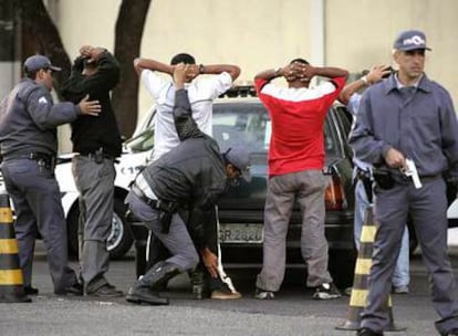 Varios policías cachean a cuatro hombres en São Paulo.