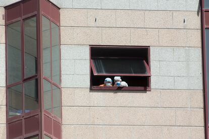 Trabajadores de la residencia de mayores DomusVi intervenida en Outeiro de Rei (Lugo) se asoman a una ventana.