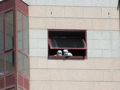 Trabajadores de la residencia de mayores DomusVi intervenida en Outeiro de Rei (Lugo) se asoman a una ventana.