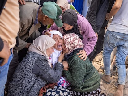 TOPSHOT - Women react as volunteers recover the body of a familly member from the rubble of collapsed houses in the village of Imi N'Tala near Amizmiz in central Morocco after the deadly 6.8-magnitude September 8 earthquake, on September 10, 2023. Using heavy equipment and even their bare hands, rescuers in Morocco on September 10 stepped up efforts to find survivors of a devastating earthquake that killed more than 2,100 people and flattened villages. (Photo by FADEL SENNA / AFP)