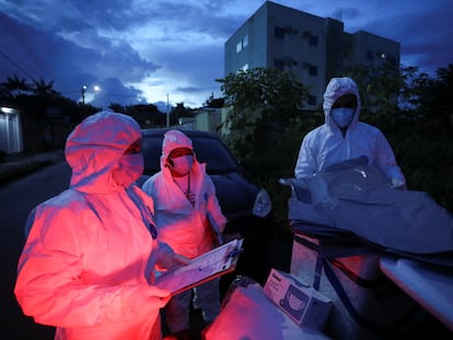 Agentes de saúde municipais se preparam para examinar o corpo de uma pessoa em meio ao surto de coronavírus em Manaus.