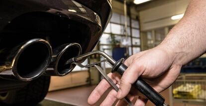 Un técnico inserta una sonda detectora en el tubo de escape de un automóvil en un garaje.