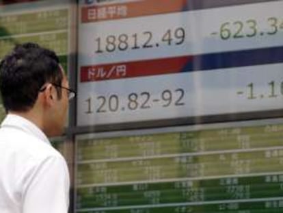 Un hombre mira un panel electrónico con información económica global sobre mercados. EFE/Archivo
