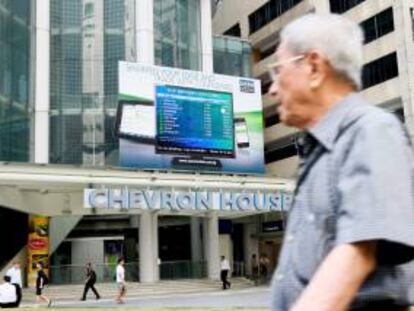 Un hombre camina junto a una pantalla que muestra la información de la bolsa en Singapur. EFE/Archivo