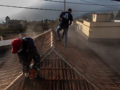 Moduo y Federico limpian la ceniza de un tejado en una casa en El Paso, uno de los municipios más cercanos al volcán.