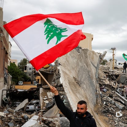 A man waves a Lebanese flag as he stands amidst the rubble of a building destroyed in Israeli strikes, after a ceasefire between Israel and Iran-backed group Hezbollah took effect at 0200 GMT on Wednesday after U.S. President Joe Biden said both sides accepted an agreement brokered by the United States and France, in Tyre, Lebanon, November 27, 2024. REUTERS/Adnan Abidi       TPX IMAGES OF THE DAY     