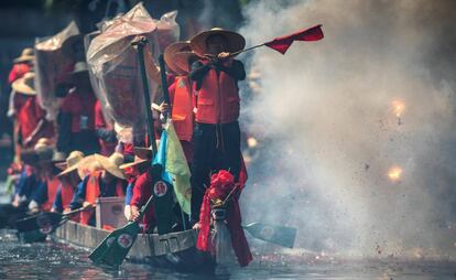 Un grupo de remeros realiza un espectáculos con pirotecnia durante una carrera de barcos de dragón, en Guangzhou, China.