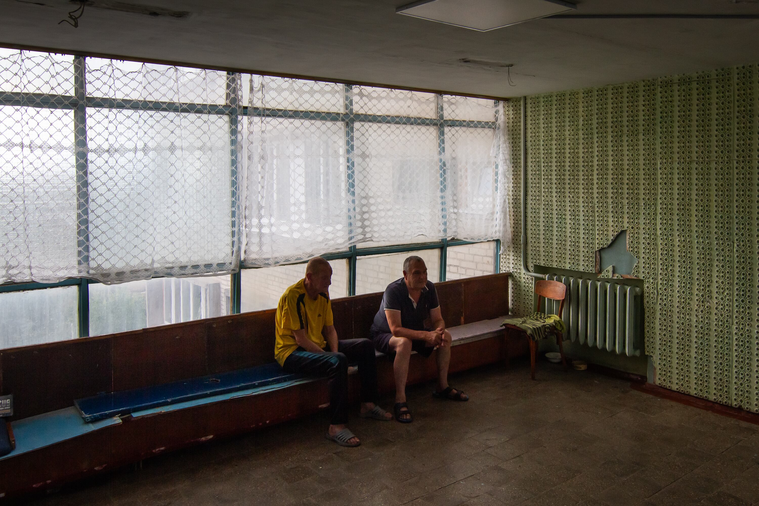 Dois homens que residem num centro para deslocados internos em Kharkiv (Ucrânia) conversam no patamar de um dos andares.