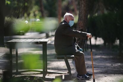 Un anciano con mascarilla descansa en el Parque Calero en Madrid.