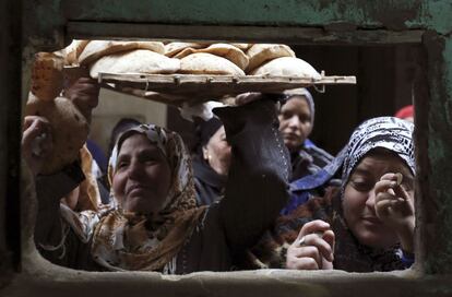 Una mujer lleva el pan recién comprado en una panadería de El Cairo (Egipto) donde utilizan una tarjeta electrónica vinculada al documento de identidad para distribuir el pan subvencionado, así los cairotas no tienen que luchar para conseguirlo.