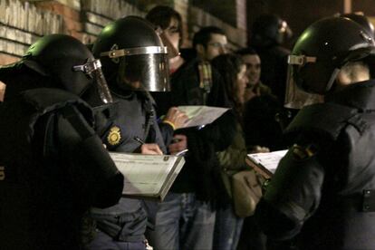 Un grupo de policías antidisturbios anotan los nombre de varios de los manifestantes en la cuesta Moyano de Madrid.