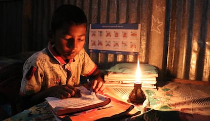 Un niño hace sus tareas escolares en su casa, bajo la luz de una vela, en una aldea de Bangladés.