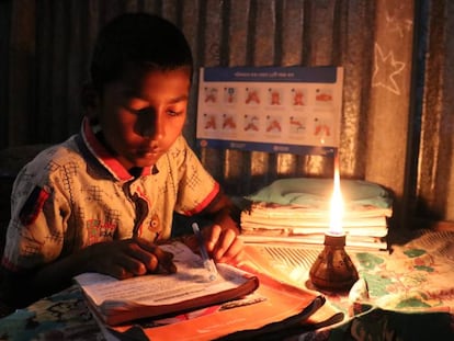 Un niño hace sus tareas escolares en su casa, bajo la luz de una vela, en una aldea de Bangladés. 