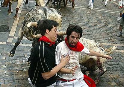 Dos mozos tratan de librarse de una cogida en la curva de la calle de Mercaderes.