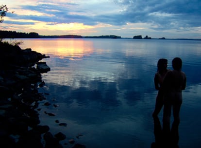 Una pareja de naturistas contempla el atardecer.