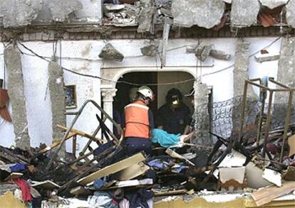 Los bomberos trasladan a una de las tres personas fallecidas a consecuencia de la explosión.