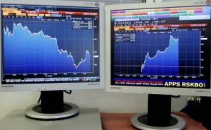 Pantallas con las gráficas de evolución del IBEX35 (i) y de la prima de riesgo (d), en la jornada de ayer.