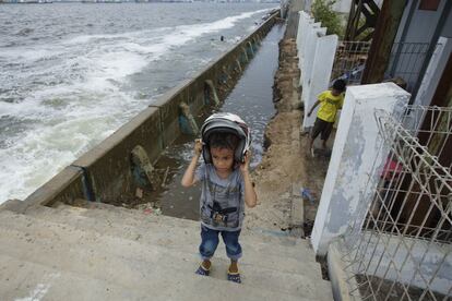 Un niño pasa junto a un dique en la costa norte de Yakarta (Indonesia) después de pescar con su padre. La mayor ciudad del sudeste de Asia se está hundiendo lentamente en el mar, en gran parte al consumo excesivo de agua subterránea.