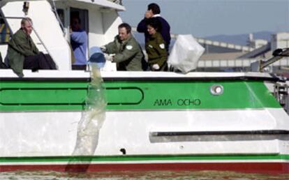 Técnicos de la Junta de Andalucía recogen agua en la zona donde se hundió la gabarra.