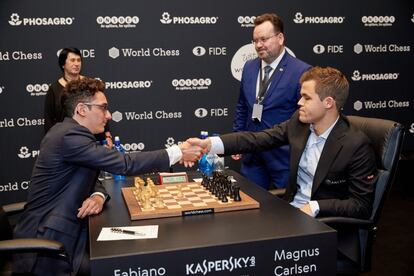 Caruana y Carlsen se saludan al inicio de la 1ª partida del Mundial ante los árbitros, Stéphane Escafre y Nana Alexandria