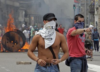 Dos jóvenes con tornillos en las manos y el rostro tapado ante una barricada formada en Beiramar, ayer.
