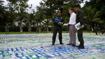 O presidente da Colômbia, Juan Manuel Santos, e dois agentes sobre as mais de 12 toneladas de cocaína apreendida