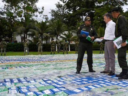 O presidente da Colômbia, Juan Manuel Santos, e dois agentes sobre as mais de 12 toneladas de cocaína apreendida