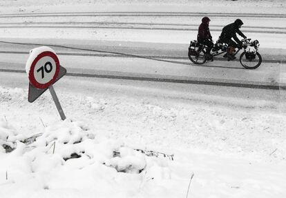 Una pareja de turistas circula hoy por la N-135 cubierta por la nieve, en el puerto de Ibañeta, el 29 de octubre de 2018.