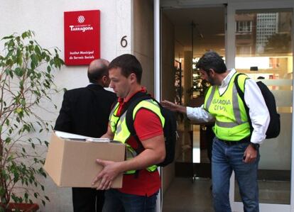 Agentes con documentaci&oacute;n saliendo de Servicios Sociales.