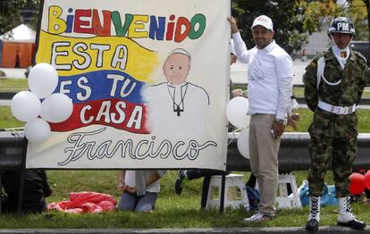 Un hombre sostiene un cartel de bienvenida mientras espera el paso del papa Francisco en Bogotá (Colombia).