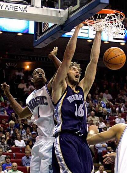 El jugador de los Grizzlies Pau Gasol machaca canasta en presencia del jugador de los Magic Trevor Ariza.