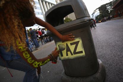 Una estudiante pinta con spray la palabra paz en una papelera en Caracas, 17 de febrero de 2014.