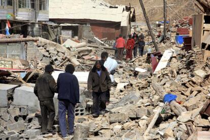Varios vecinos caminan sobre los escombros de los edificios destruídos por el terremoto que ha arrasado la región de Qinghai.