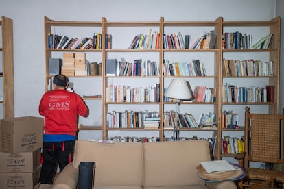 Un operario de mudanzas retira los libros de las estanterías donde habían estado 30 años. 