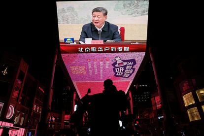 Un motorista pasa junto a una pantalla en la que aparece el presidente chino Xi Jinping en la reunión del partido comunista chino, en Beijing, China.