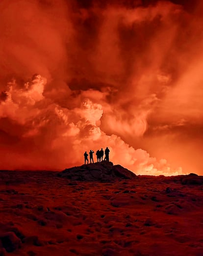 Un grupo de personas observan la nube de humo generada por la erupción un volcán en la península de Reykjanes (Islandia).
