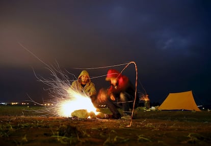 Refugiados sirios se calientan en un campo de refugiados entre la frontera de Grecia y Macedonia.