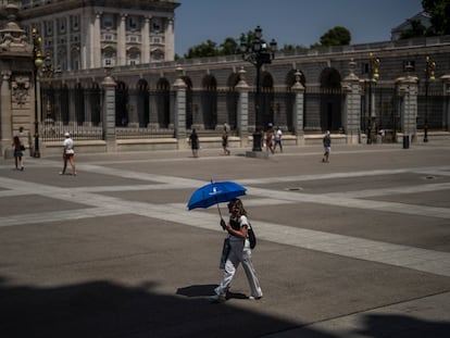A woman shelters from sun with an umbrella in front of the Royal Palace during a hot a sunny day in Madrid, Spain, Monday, July 18, 2022. (AP Photo/Manu Fernandez)