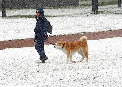 Una joven pasea con su perro por el Parque Yamaguchi de Pamplona, que esta mañana amaneció cubierta por la nieve.