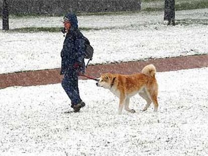 Una joven pasea con su perro por el Parque Yamaguchi de Pamplona, que esta mañana amaneció cubierta por la nieve.