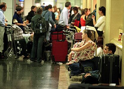 Pasajeros esperando ayer sus vuelos en el aeropuerto de Barajas.
