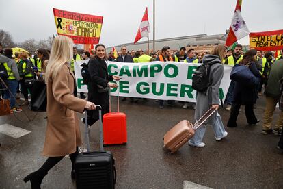 Varias turistas pasan con sus maleas ante la concentración de agricultores este jueves en el centro de Madrid. 