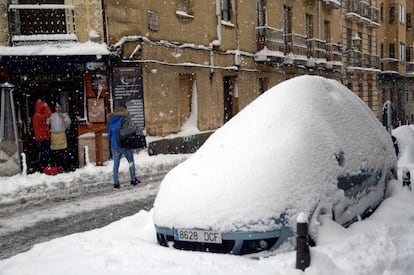 Un vehículo aparcado en una calle del centro de Segovia aparece totalmente cubierto por la nieve, que seguía cayendo a primera hora de la mañana, donde en algunos puntos ha superado los cuarenta centímetros.