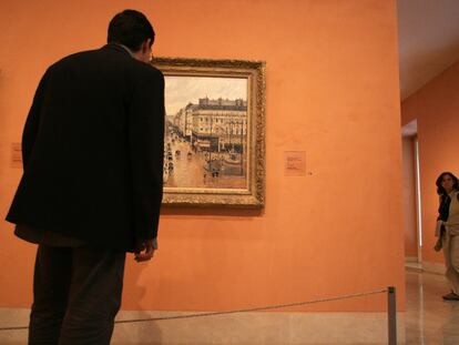 Un visitante observa el cuadro 'Rue Saint-Honoré por la tarde. Efecto de lluvia', de Camille Pisarro, en el museo Thyssen-Bornesmisza de Madrid.