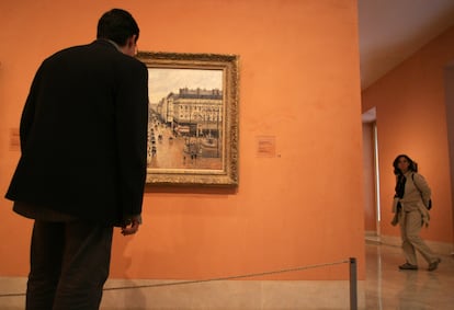 An unidentified visitor looks at an impressionist painting by Camille Pissarro called the Rue Saint-Honore